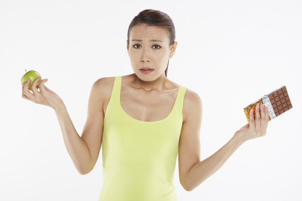 Woman deciding between an apple and a chocolate bar